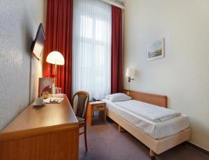 a hotel room with a bed and a desk and a window at Acom Hotel Berlin Kurfürstendamm in Berlin