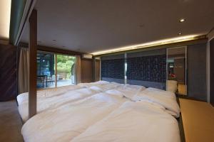 a large bed with white sheets in a bedroom at Sauna Villa Biwako Forest Bathing in Takashima