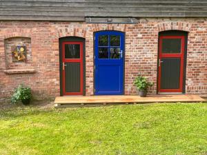 a brick house with a blue door and a deck at Gästescheune Rubitz in Rubitz