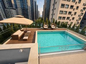 a swimming pool with an umbrella and some buildings at Jamsil Orosie Hotel in Seoul
