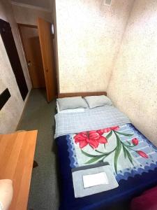 a small bedroom with a bed with a blue comforter with flowers at Гостиница Гулдер in Almaty