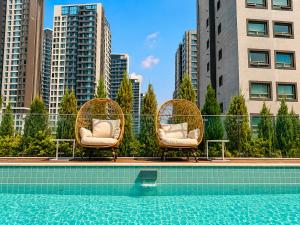 two wicker chairs sitting next to a swimming pool at Jamsil Orosie Hotel in Seoul