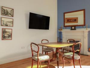 a dining room with a table and chairs and a tv at Farthings, The Old Chapel in St Austell