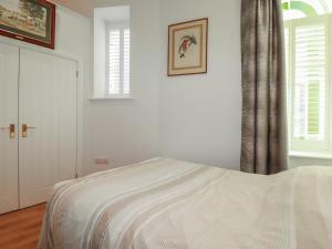 a white bedroom with a bed and two windows at Farthings, The Old Chapel in St Austell