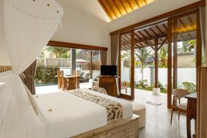 a bedroom with a bed and a television and a patio at Alam Dania Cottage in Ubud