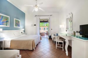 a bedroom with a bed and a desk and a television at iGV Club Baia Samuele in Sampieri +62 photos