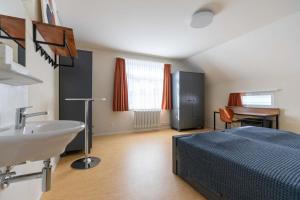 a bedroom with a bed and a sink and a desk at Centrally Located Room in Buchs