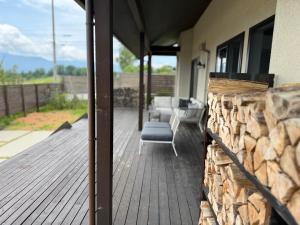 a porch with a chair and a stack of logs at 南アルプスを望むサウナ付き宿,田園風景,全室エアコン,バーベキュー可 in Hokuto