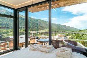 a bedroom with a bed and a balcony with mountains at Capsule & Enesai Hotels Karakol in Karakol