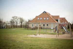 a playground in front of a house with a slide at Weidevilla XXL in Hollum