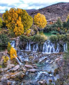 una cascada en medio de una montaña con árboles en Apartamentos El Pajar del Abuelo, en Peralejos de las Truchas