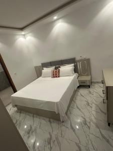 a bedroom with a large white bed and a table at Bayt Noor in Dakar