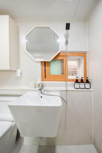 a white bathroom with a sink and a window at Stay ongyeol in Suwon