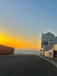 an empty street in front of the ocean at sunset at High tide complex in Langstrand