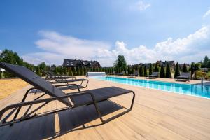 a row of lounge chairs next to a swimming pool at Aparthotel Diamond SPA Aqua in Białka Tatrzańska