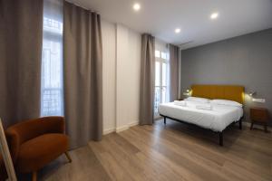 a bedroom with a bed and a chair and windows at Apartamento Nova by Cartagena Spain in Cartagena