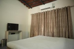 a bedroom with a white bed and a curtain at Shunyata Eco Resort Junagadh in Vadal