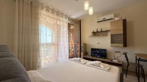 a bedroom with a white bed and a window at Bratanov Cascadas Ravda in Ravda