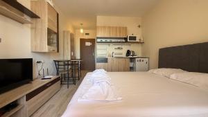 a large white bed in a room with a kitchen at Bratanov Cascadas Ravda in Ravda +41 photos