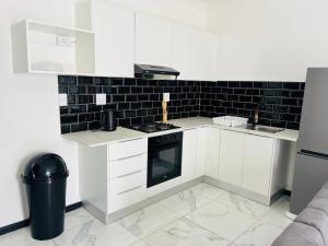 a kitchen with white cabinets and a black tile wall at Lady Victoria in Walvis Bay