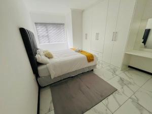 a white bedroom with a bed and a window at Lady Victoria in Walvis Bay
