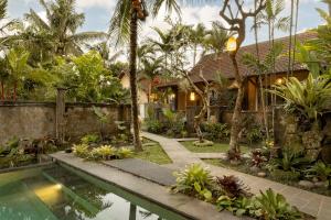 a villa with a swimming pool in front of a house at Alam Dania Cottage in Ubud