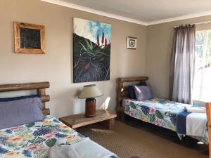 a bedroom with two beds and a table with a lamp at Dullstroom on the Dam in Dullstroom