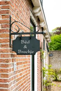 a sign for a bed and bicycle attached to a brick building at B&B Stinzenflora - Gezellige accommodatie tussen groen en historie in Cornjum