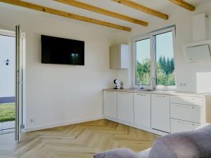 a kitchen with white cabinets and a flat screen tv at Domki Różane Nad Stawem in Stopnica +18 photos