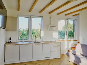 a kitchen with white cabinets and windows and a couch at Domki Różane Nad Stawem in Stopnica