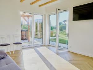 a living room with sliding glass doors and a couch at Domki Różane Nad Stawem in Stopnica