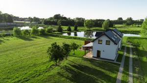 a house in a field next to a river at Domki Różane Nad Stawem in Stopnica