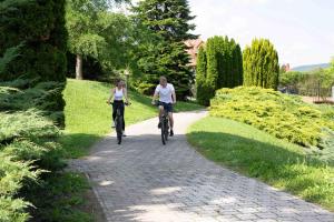 two people riding bikes down a path in a park at Hotel Carbona Thermal Spa in Hévíz