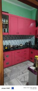 a kitchen with red cabinets and pots and pans at Gyan Nivas in Bareilly