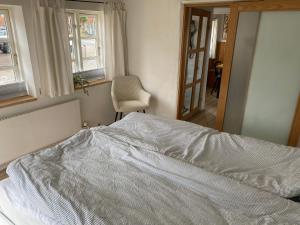 a bedroom with a bed and a chair and windows at Byhus Bogense in Bogense +6 photos