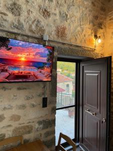 a flat screen tv hanging on a stone wall next to a window at Mesovouni Stone Suites 1 in Mesovounion-Zagori