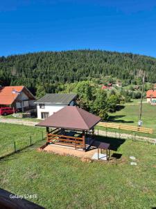 a picnic table with a roof in a field at Brvnara K2 KONAK in Šljivovica