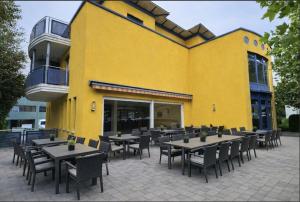 ein gelbes Gebäude mit Tischen und Stühlen davor in der Unterkunft HelloStay Zug Studios in Hünenberg