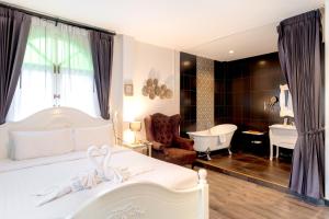 a bedroom with a white bed and a bath tub at Nidhra Lanna Hotel Chiang Mai in Chiang Mai +108 photos