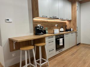 a kitchen with white cabinets and a counter with stools at Apartament Rynek 17 in Krosno