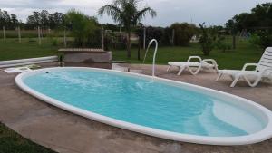 a large swimming pool with two chairs and a table at La Felicidade in Villa Elisa