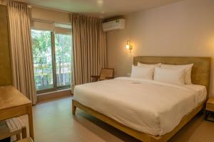 a bedroom with a large white bed and a window at The Ten in Siolim