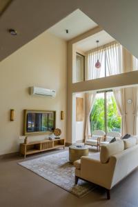 a living room with white furniture and a large window at The Ten in Siolim