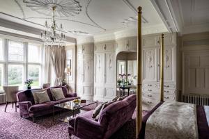 a living room with a bed and chairs and a chandelier at Woodlands Park Hotel in Cobham +31 photos