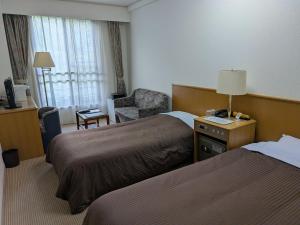 a hotel room with two beds and a chair at Shirafune Grand Hotel in Matsumoto +28 photos
