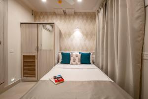 ein Schlafzimmer mit einem großen Bett und blauen Kissen in der Unterkunft Anthurium Hotel in Mapusa