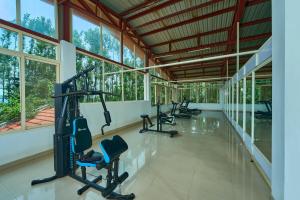 a gym with treadmills and ellipticals in a building with windows at Coffee Grove Resort in Chikmagalūr