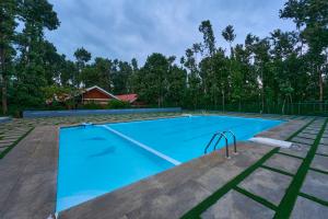 an empty swimming pool with blue water in a yard at Coffee Grove Resort in Chikmagalūr