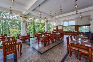 a restaurant with wooden tables and chairs and windows at Coffee Grove Resort in Chikmagalūr