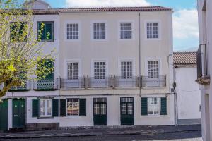 a large white building with green shutters and a balcony at GuestReady - Doctor House in Horta